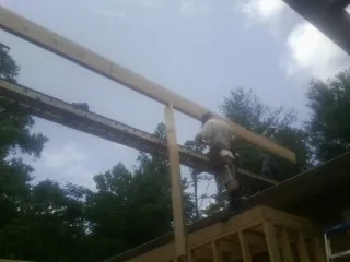 Carpenter setting a ridge beam over a new addition frame — Ice Dam Removal by Roofing Brothers in Bluemont