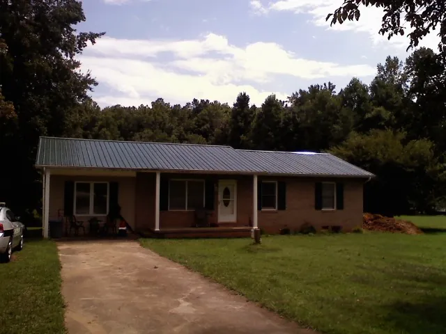 Dark green metal roof on a brick ranch with a covered porch in Bluemont