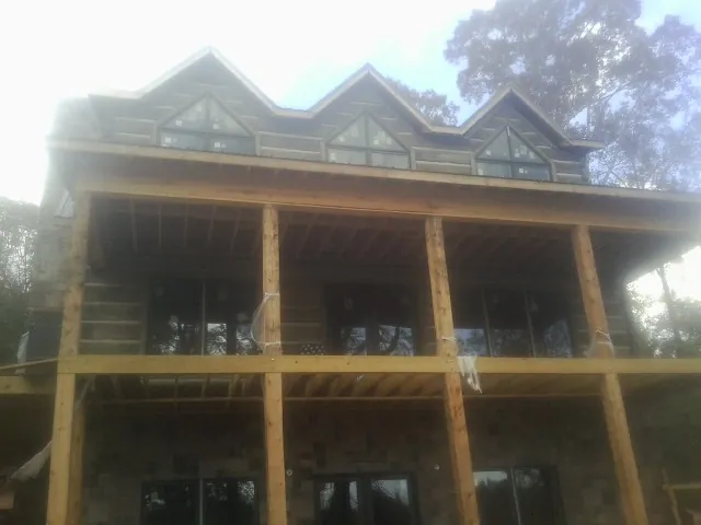 Dormers and porch framing on a large log home under construction — Roof Coating work by our crew in Bluemont