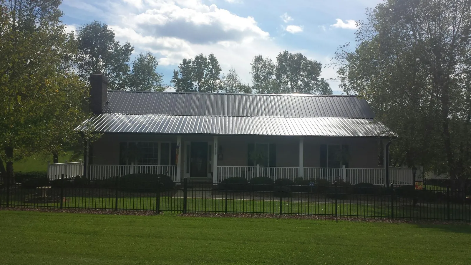 Gray metal roof on a brick ranch with a full width front porch — Gutter Guard Installation work by our crew in Bluemont