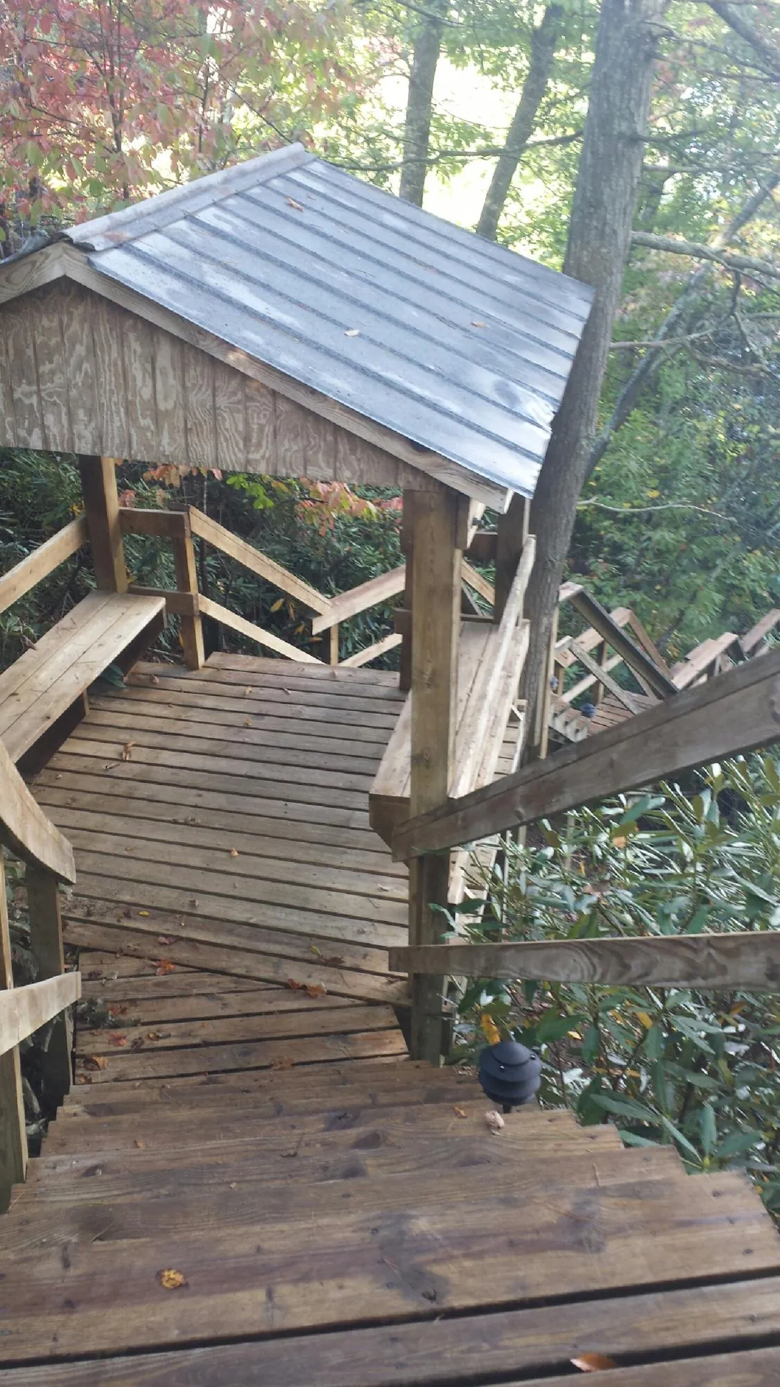 Metal roofed shelter over wooden steps on a wooded walkway — Skylight Repair & Installation work by our crew in Bluemont