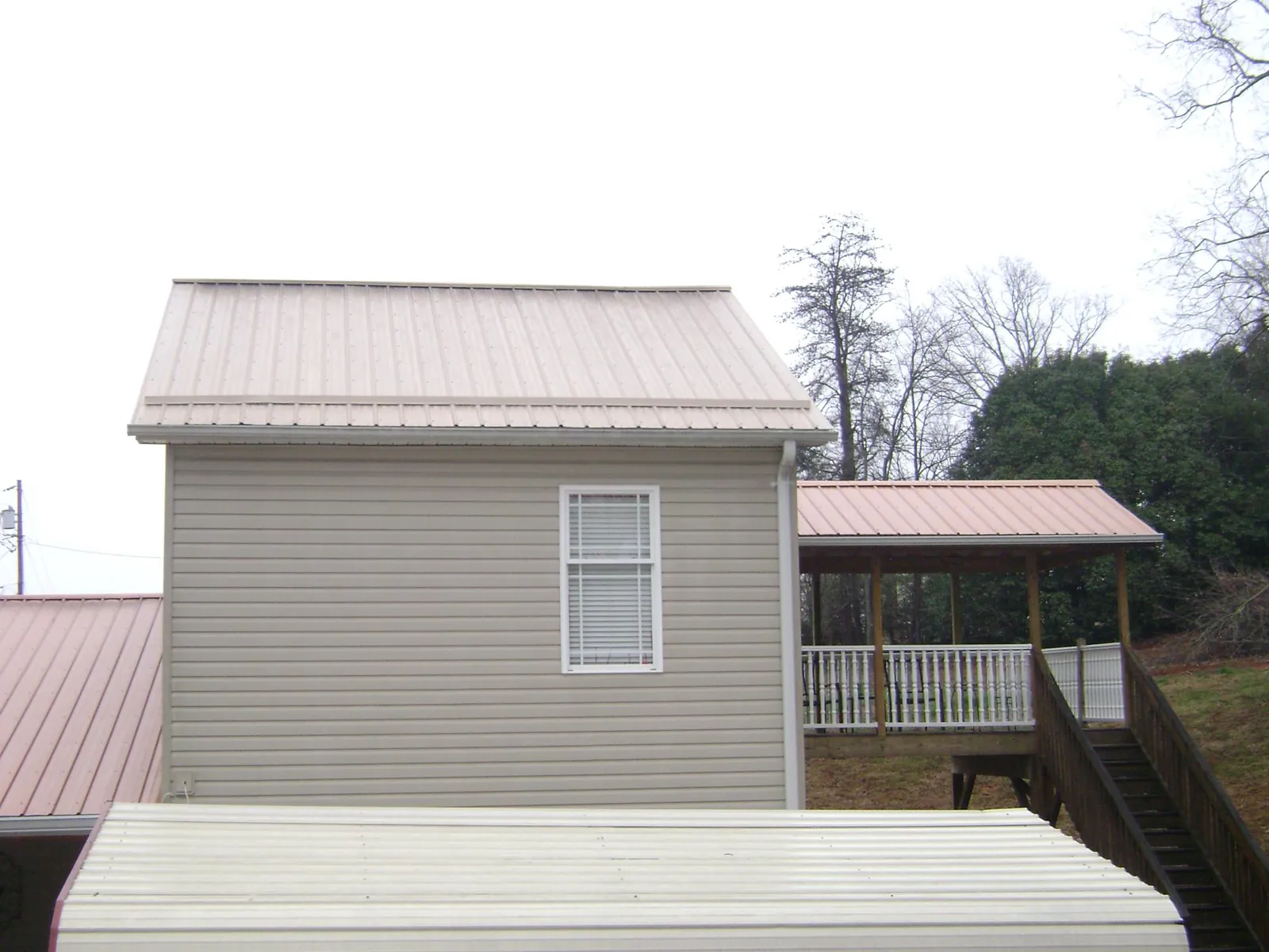 Tan metal roofs on a two story addition and attached porch, from a Roof Replacement job in Bluemont