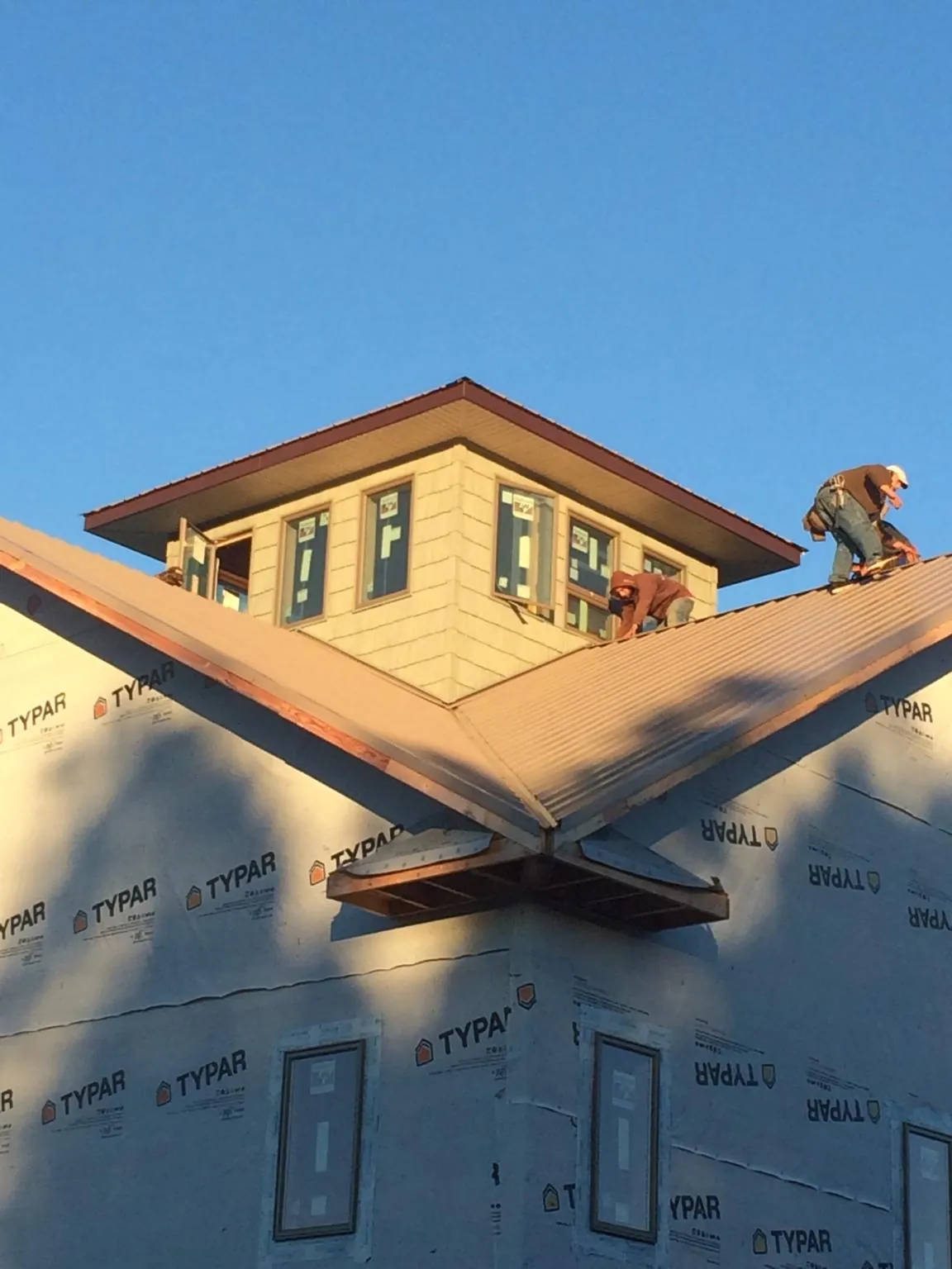Roofers working around a rooftop cupola on a new metal roof at sunset — Roof Waterproofing in Bluemont by Roofing Brothers